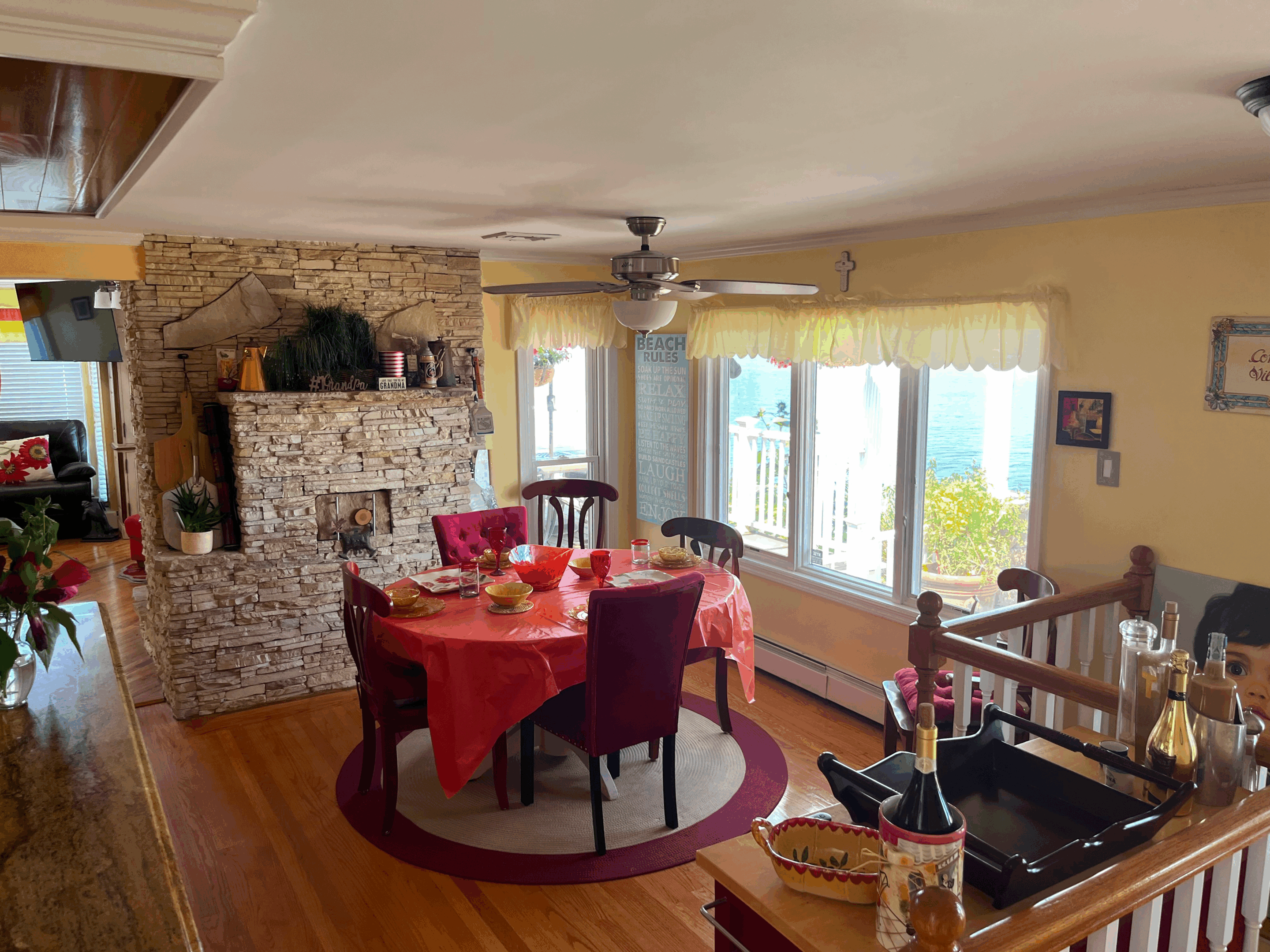Cozy dining room with round table, red chairs, and stone fireplace.