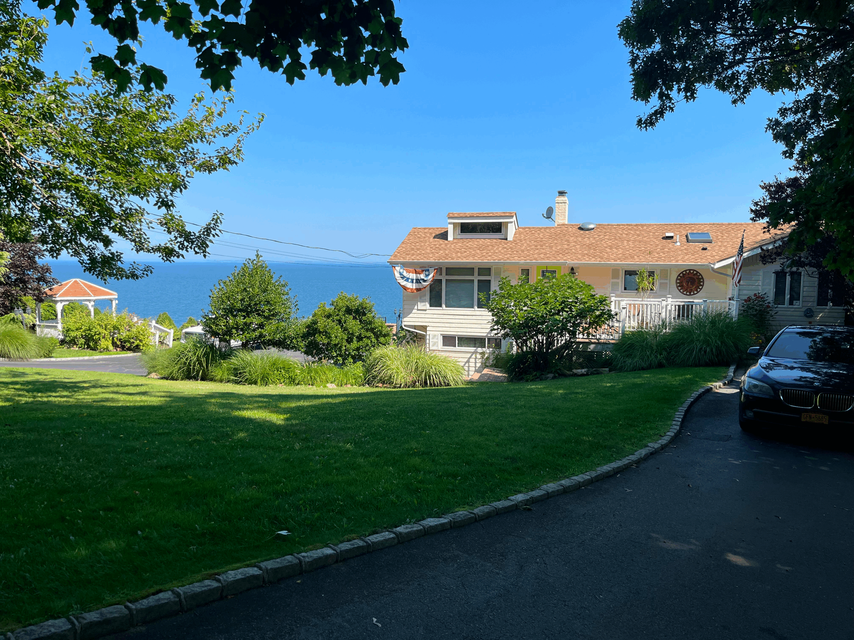 A scenic view of a house near the ocean with a green lawn and pathway.