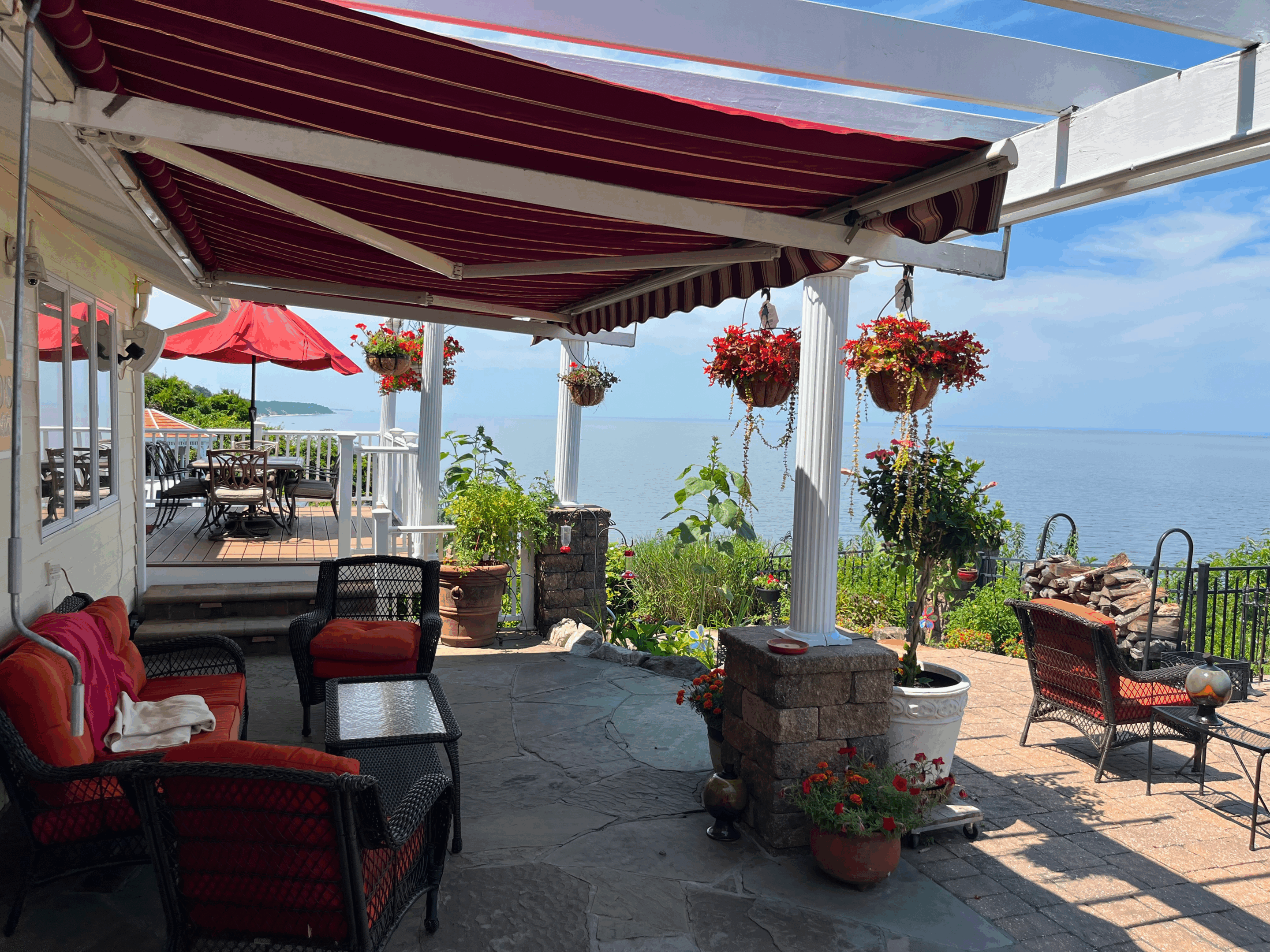 Sunny outdoor patio with hanging flowers and ocean views.