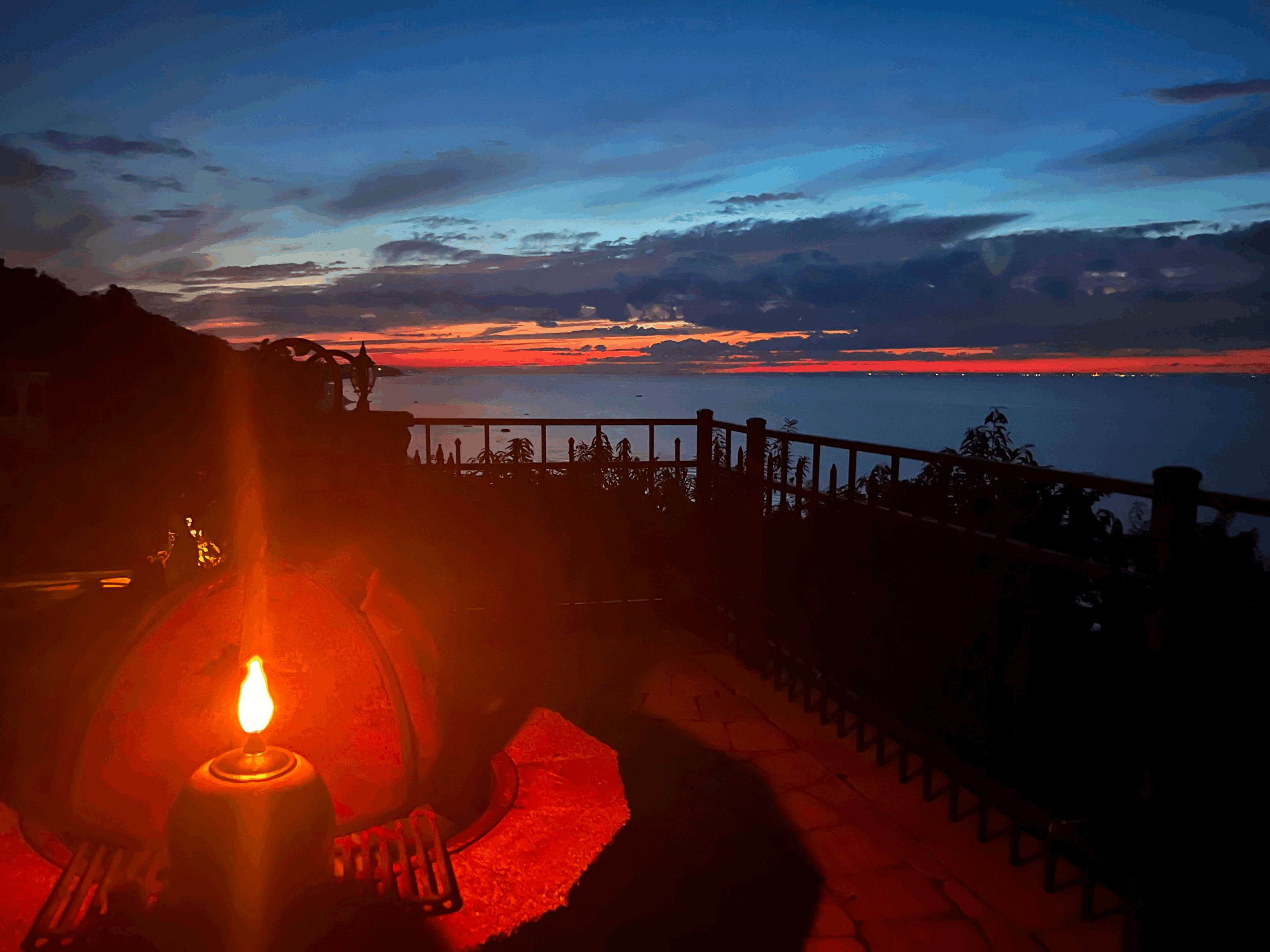 Cozy outdoor fire pit at sunset with a wooden deck overlooking the ocean.