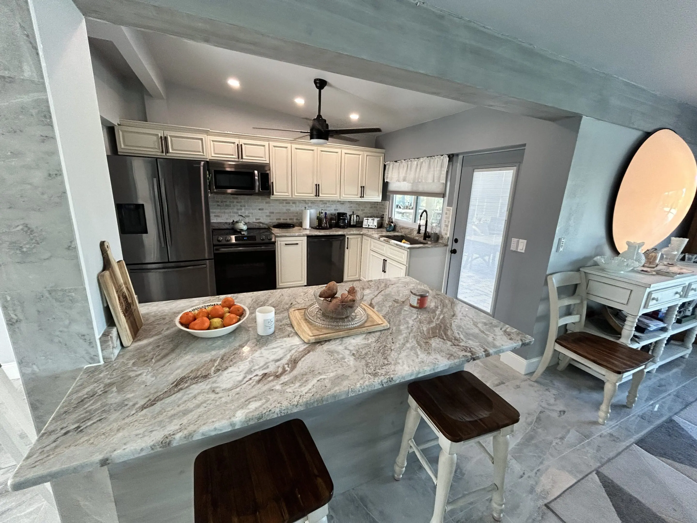 Modern kitchen with marble countertops and stainless steel appliances.