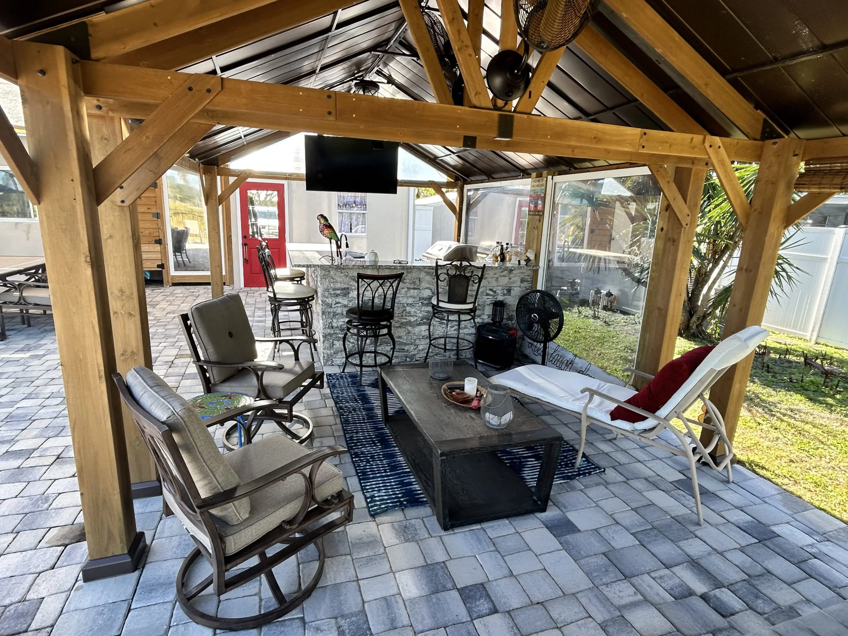 Cozy outdoor seating area with rocking chairs and a bar under a wooden pergola.