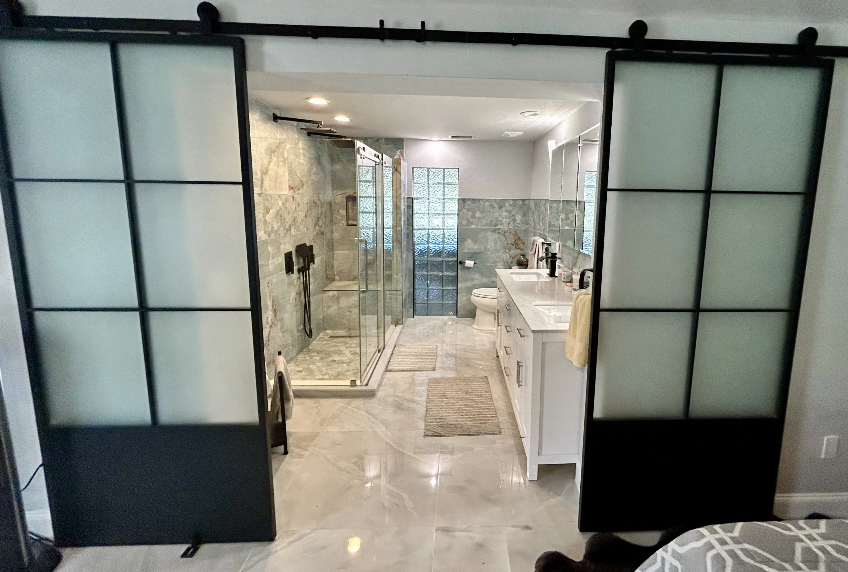 Modern bathroom with glass shower and sliding doors.