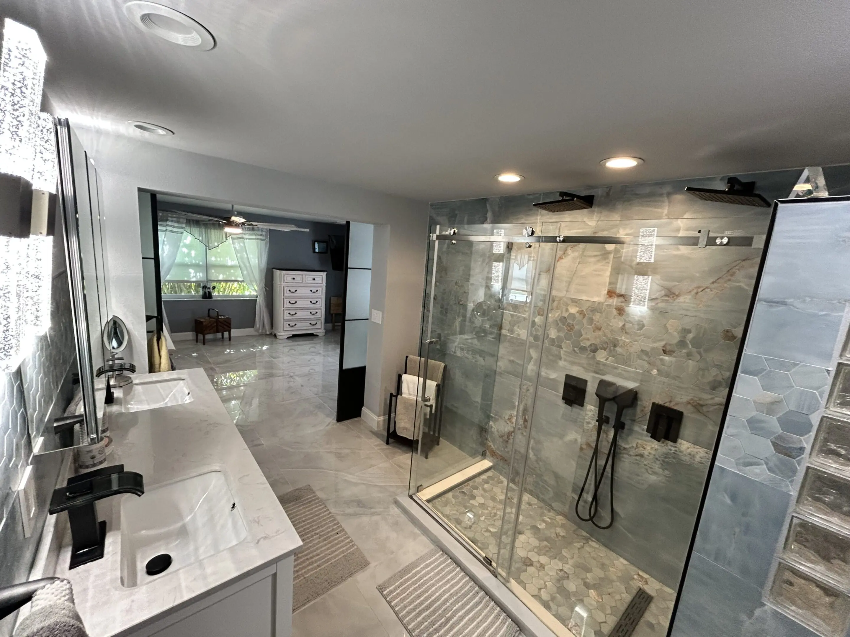 Modern bathroom with double sinks and glass-enclosed shower.