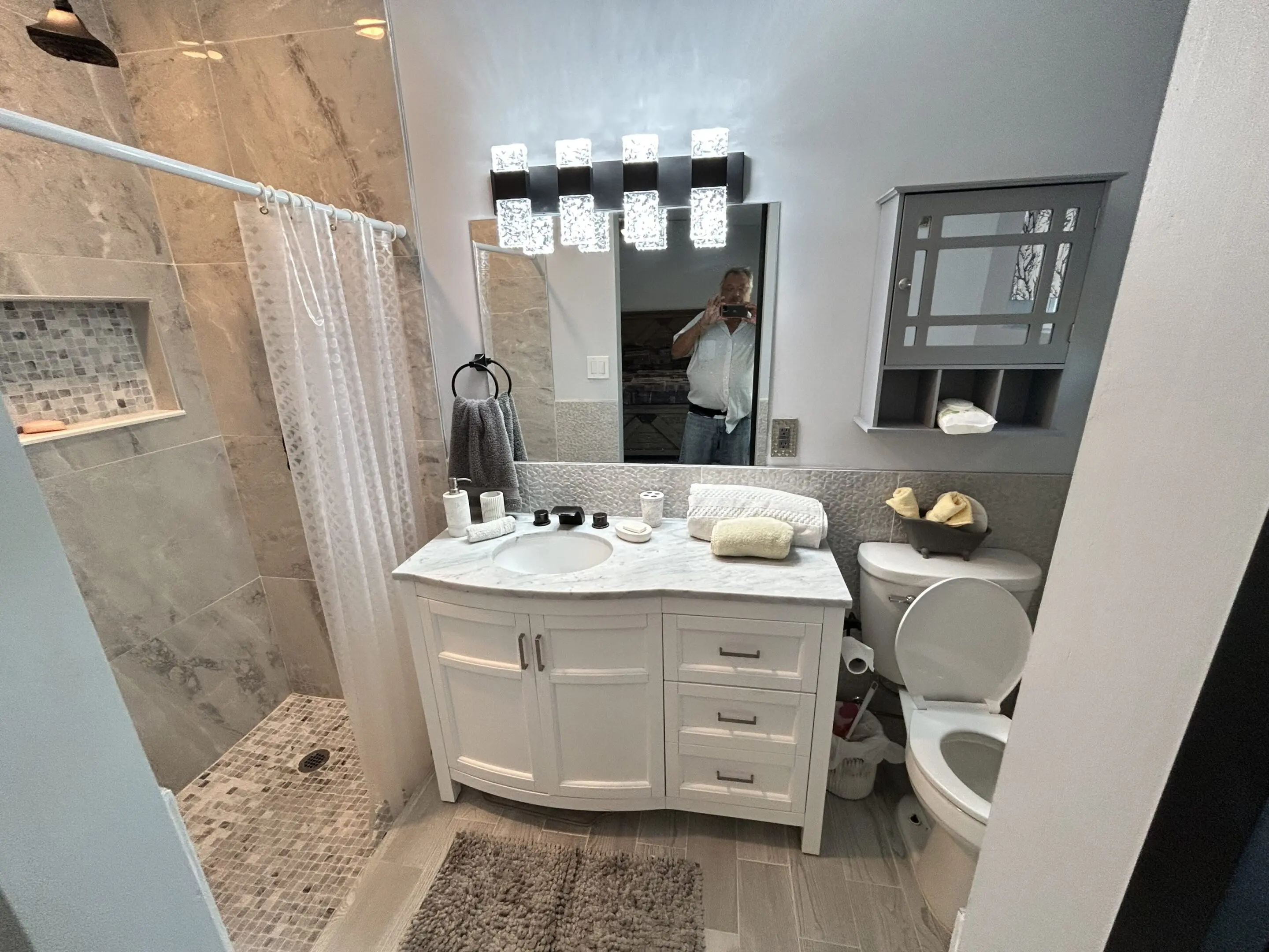 Modern bathroom with white vanity and glass-enclosed shower.